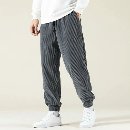 View of relaxed fit jogger pants in dark gray, featuring an elastic waistband and tapered legs