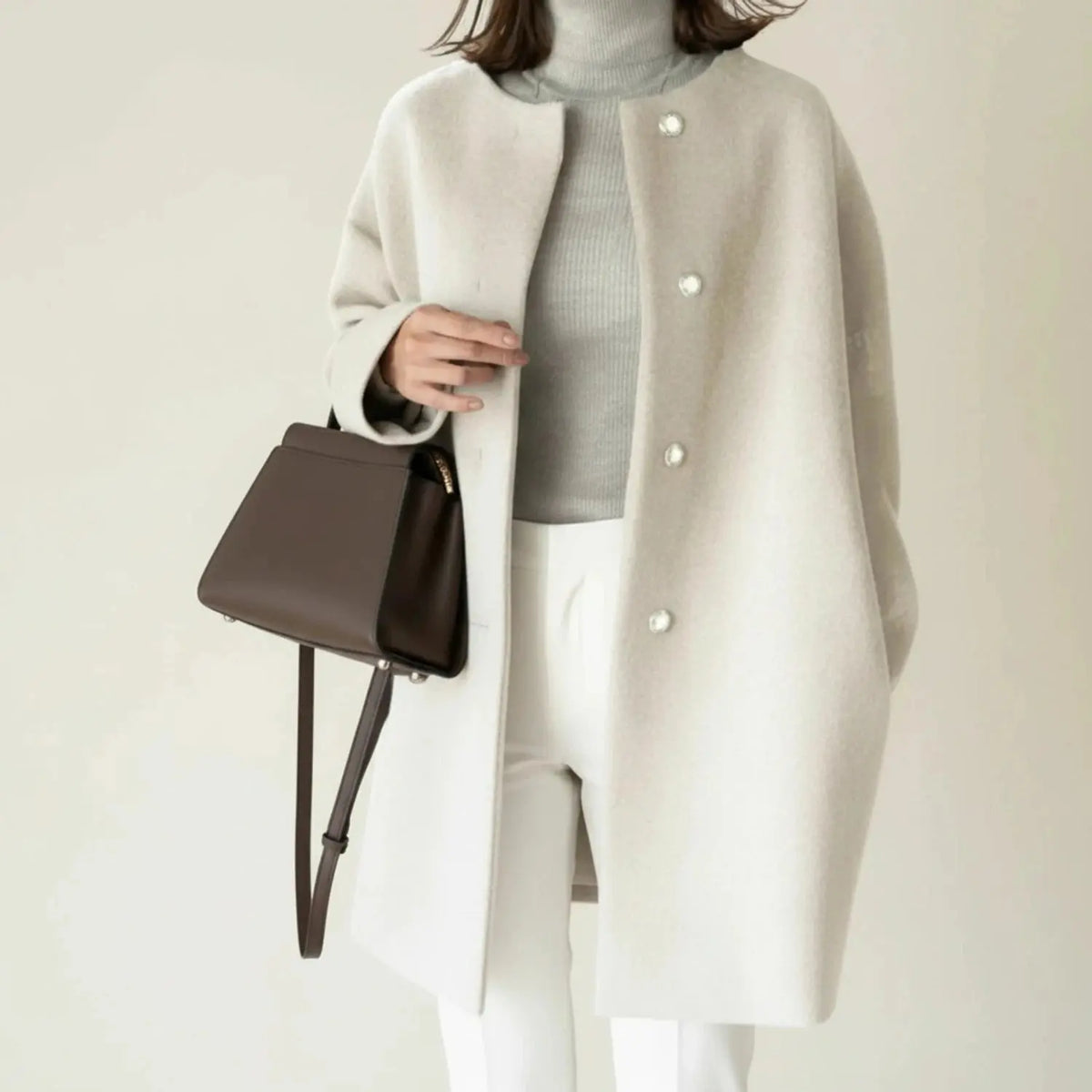 View of a stylish minimalist winter coat in soft gray, featuring a tailored fit and sleek silhouette