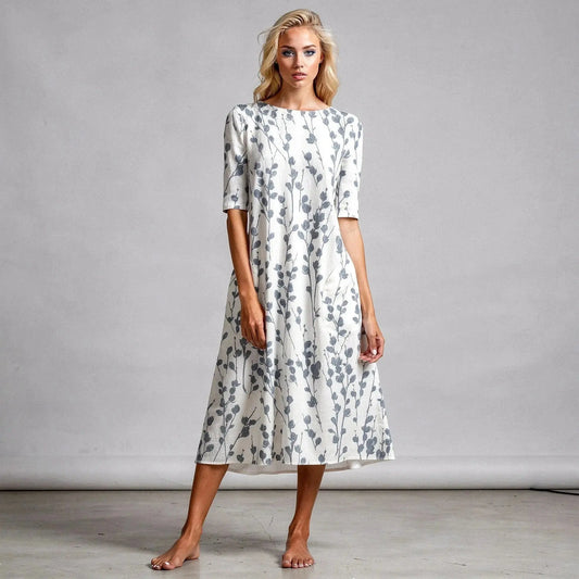 Woman wearing white A line midi dress with grey floral pattern, standing barefoot on light background
