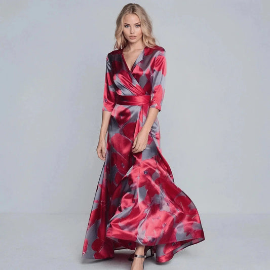Woman wearing a red and gray floral V neck maxi dress, standing with hands at sides, slight smile
