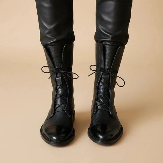 Black ankle boots with a sleek minimalist design, featuring a smooth leather finish and a view showing the heel