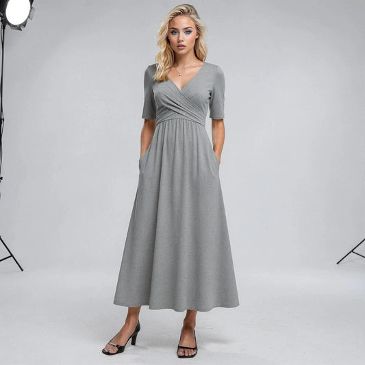 Woman wearing a gray midi dress with short sleeves, V neckline, and hands in pockets, standing
