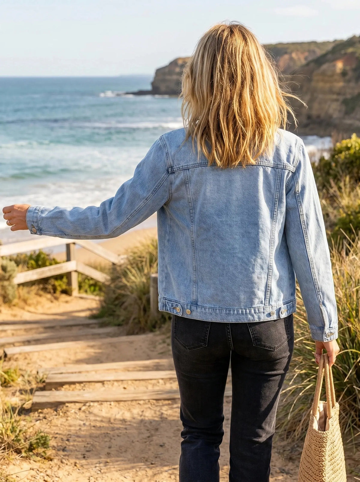 View of a light blue denim jacket with a relaxed fit, featuring a classic collar and two pockets